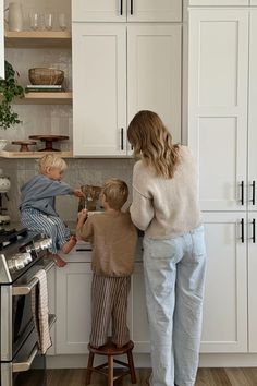 a woman and two children are in the kitchen