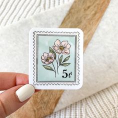 a person holding up a stamp with flowers on it