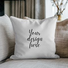 a white pillow with the words your design here printed on it sitting on a couch