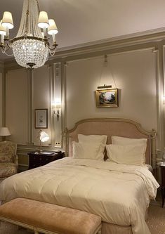 a bedroom with a large bed, chandelier and two lamps on the wall