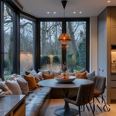 a living room filled with lots of furniture and large windows overlooking the trees in the background