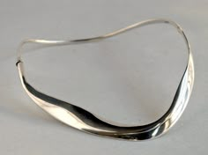 "* Vintage sterling silver choker necklace * Material: sterling silver * Clasp: sliding box clasp * Length: 16 2/8 inches * Inner width: 4 1/4 inches across widest point This is a stunning piece of masterful metalsmithing by Spanish Modernist Juli Guasch. This unique vintage necklace is hand fabrated in Spain in the 1970's or early 1980's. The necklace is made in heavy sterling silver in fluid, flowing lines that form an asymmetrical, abstract closed ring. This closed circular collar opens on the right side by pushing a tiny slide clasp; the front and back elements open via a hinge on the left side. An elegant, well crafted piece. The necklace measures about 9/16\" at the widest point in the front and 1/8\" wide in the back of the piece. When closed, the inner measurement of the necklace i Luxury Modernist White Gold Jewelry, Modern Sterling Silver Choker Necklace, Silver Polished Choker Jewelry, Contemporary Adjustable Formal Jewelry, Contemporary Formal Necklaces With Polished Finish, Modern Sterling Silver Clasp Jewelry For Anniversary, Contemporary Polished Necklace For Formal Occasions, Adjustable Modernist Sterling Silver Jewelry, Contemporary Hallmarked Jewelry As Gift