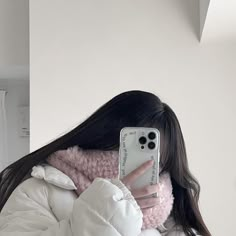 a woman taking a selfie with her phone in front of her face and wearing a white coat