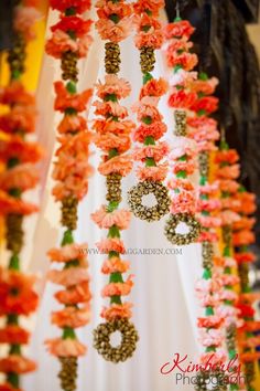 an arrangement of flowers and numbers hanging from the ceiling at a wedding in orange and pink colors