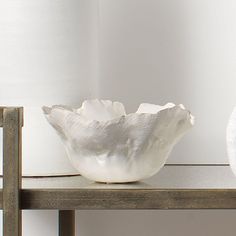 a white vase sitting on top of a wooden shelf next to a roll of toilet paper