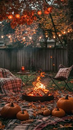 an outdoor fire pit surrounded by pumpkins and plaid blankets with lights hanging above it