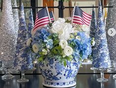 a blue and white vase filled with flowers on top of a table next to candles