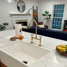 a kitchen counter with a sink and some bananas on the counter top in front of a fireplace