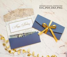 two blue envelopes tied with gold ribbon on top of a marble table next to each other