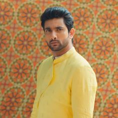 a man standing in front of a wall with an orange and yellow pattern on it