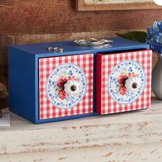 two blue and red boxes sitting on top of a counter next to a vase with flowers