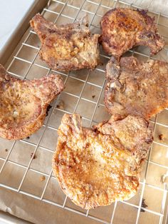 four steaks sitting on top of a metal rack