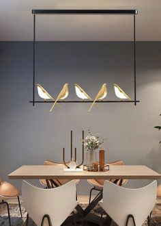 a dining room table with four birds hanging from it's ceiling light above it