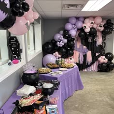 a purple table topped with lots of black and white balloons next to a wall filled with halloween decorations