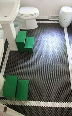 a white toilet sitting next to a sink and a green box on the floor in a bathroom