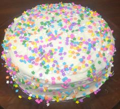 a cake with white frosting and colorful sprinkles