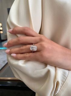 a woman's hand with a diamond ring on her left wrist, wearing a cream colored dress