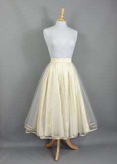 This show stopping skirt is made from a layer of Champagne coloured silk dupion with two layers of tulle hemmed in Gold trim. The tulle layers are a double circle which means lots and lots of volume! Wear with a 'Swing' petticoat for extra swish on the dance floor! Seen in the last photo without a petticoat underneath. The skirt is designed to be worn quite high on the waist and has a snug fitting waistband so please check your own measurement against our standard sizes before ordering. This skirt can be made in a range of standard sizes or can be made to fit your exact waist measurement if you are inbetween sizes for no extra cost. Size UK 6 is made to fit Waist 24/5"  Size UK 8 is made to fit Waist 26/27"  Size UK 10 is made to fit Waist 27/28"  Size UK 12 is made to fit Waist 29/30"  Si Elegant Tulle Skirt With Attached Cancan, Long Sheer Tulle Skirt, Silk Wedding Skirt For Summer, Summer Wedding Silk Skirt, Voluminous Silk Wedding Skirt, Silk Voluminous Skirt For Wedding, Silk Voluminous Wedding Skirt, Party Full Crinoline Skirt, Silk Wedding Skirt With Voluminous Fit