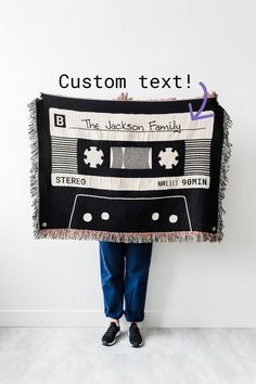 a person holding up a blanket that has an old school cassette on it