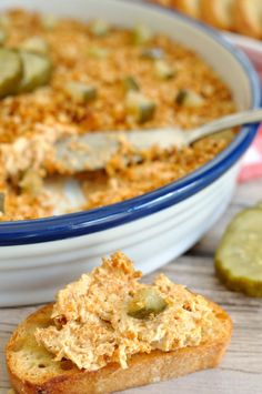 a close up of a bowl of food with bread and pickles on the side