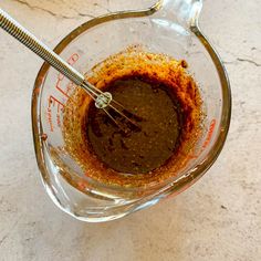 a blender filled with brown liquid on top of a white counter next to a metal whisk