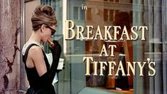 a woman walking past a store window with the words breakfast at tiffany written on it