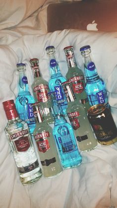 many bottles of alcohol are lined up on a bed