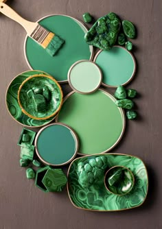 some green paint is sitting on top of plates and bowls with brush in the middle