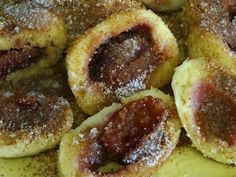 several pastries covered in powdered sugar on top of a yellow plate with red and white toppings