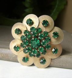 Beautiful vintage emerald green rhinestone floral pin. This vintage brooch is comprised of all emerald green rhinestones on goldtone metal in a round floral design.  Rivet back with prong-set rhinestones. Circa-1950's.  Roll-over clasp works great.  Approx. 2" across. No discolored, loose, or missing stones.  In fantastic shape! Sorry, but no international shipping at this time. Please see my shop for more vintage, estate jewelry: nightowlmemories.etsy.com Cheap Green Flower Brooches, Vintage Green Brooch Jewelry, Antique Green Brooch For Anniversary, Antique Green Brooches For Anniversary, Green Jeweled Brooch Gift, Green Jeweled Brooch For Gift, Green Rhinestone Wedding Brooch, Green Jeweled Brooches For Gifts, Green Jeweled Brooches As Gift