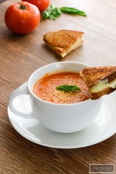 a bowl of tomato soup with grilled cheese on top