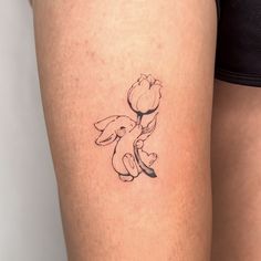 a woman's thigh with a small tattoo of a dog holding a flower on it