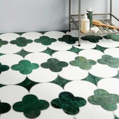 a bathroom with green and white tile on the floor next to a shelf filled with toiletries