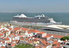 two cruise ships in the water next to some buildings and one is on the other side