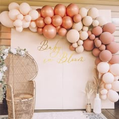 an outdoor area with balloons and a wicker chair in front of a wall decorated with flowers