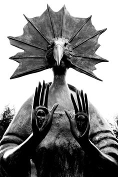 a statue with two hands in front of it and a bird on top of it