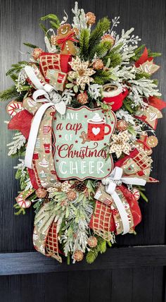 a christmas wreath hanging on the front door with coffee mugs and pineconi