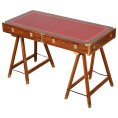 an old wooden desk with red leather top