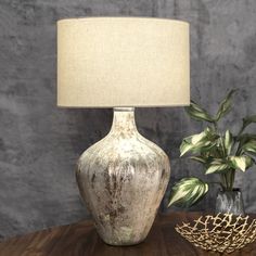 a table lamp sitting on top of a wooden table next to a potted plant