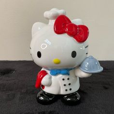 a hello kitty figurine holding a platter in its hand on a black surface