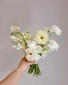 a hand holding a bouquet of white flowers