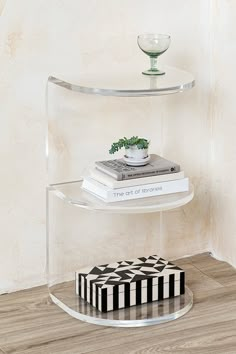 a glass shelf with books and a vase on top