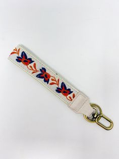 a white key fob with red, blue and orange flowers on the front side