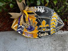 a football helmet with a bow tied to it sitting in front of some shrubbery