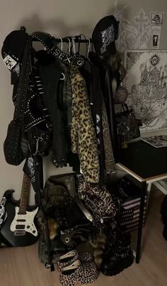 an assortment of clothes and accessories are hanging on the wall next to a table with a guitar