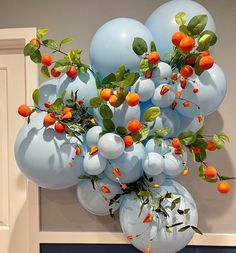 a bunch of blue balloons with oranges on them hanging from a wall in front of a door