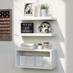 two white shelves on the wall with pictures and other items in them, one shelf is empty