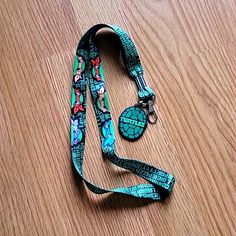 a lanyard with a turtle on it sitting on top of a wooden floor next to a pair of scissors