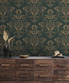 an ornate wallpaper design in gold on a green background with drawers and vases