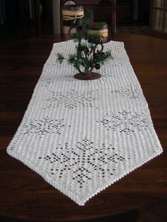 a table with a white doily on it and a potted plant in the center